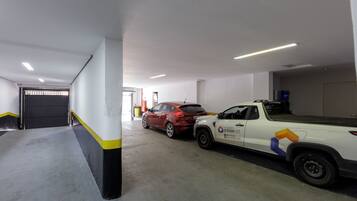A parking garage with a white pickup truck and a red car parked.