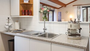 Uma cozinha com bancada de granito, pia de aço inoxidável e cafeteira.