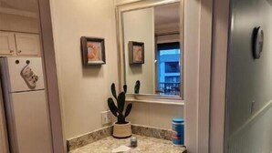 A kitchen with a granite countertop, white cabinets, a built-in oven, and a small window. - A Slice of Heaven (Myrtle Beach)