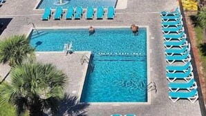 A swimming pool area with multiple pools, sun loungers, and a small waterfall feature. - A Slice of Heaven (Myrtle Beach)