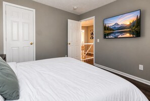 Ein Schlafzimmer mit einem Bett, einer Tür und einem Gemälde einer Berglandschaft.