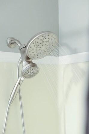 Een moderne douche met een handdouche en een vastgezette douchekop, beide met een metalen afwerking.
