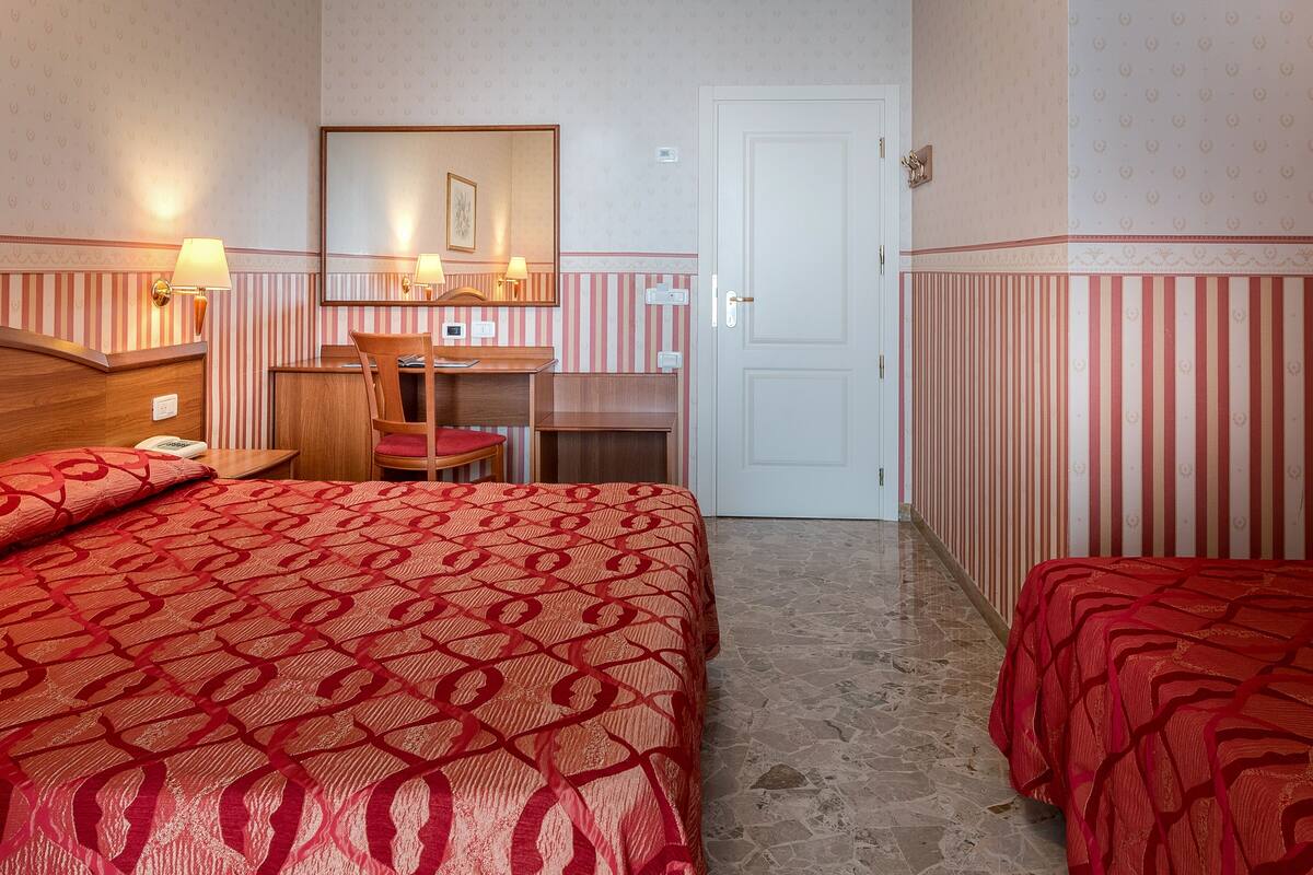 Hotellihuone, jossa on sänky, työpöytä, tuoli ja ovi.