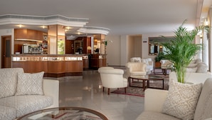 A spacious lobby with a bar area, seating arrangements, and a large potted plant. - hoteltiffany (Rimini)