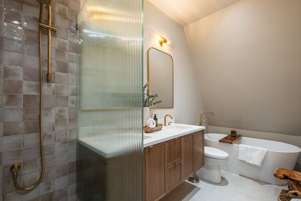 Un baño moderno con cabina de ducha de vidrio, una bañera independiente y armarios de madera.