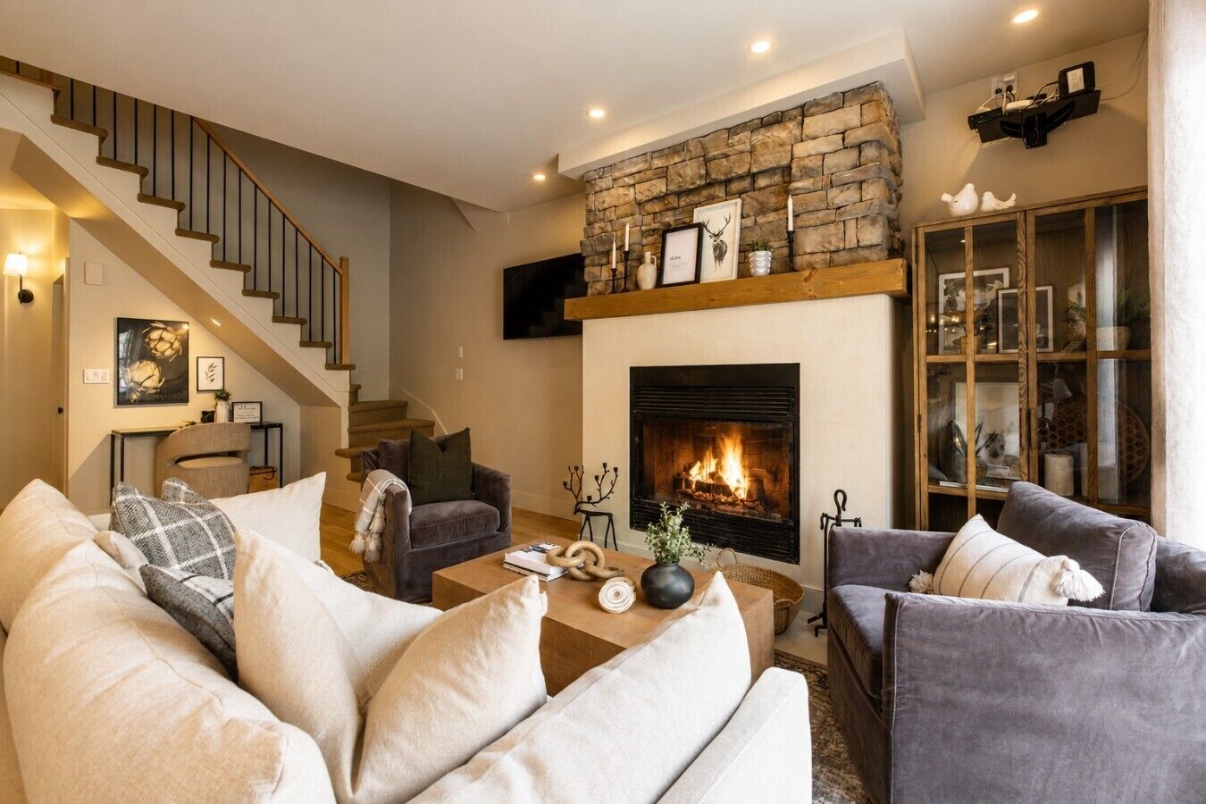 A living room with a fireplace, a staircase, and a bookshelf.