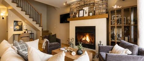 A living room with a fireplace, a staircase, and a bookshelf.