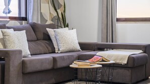 A modern living room with a grey sofa, a small round table, and a bookshelf. - White Rabbit II by Homie (Calheta)