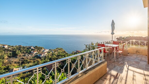 A balcony with a view of the sea, a table, chairs, and a decorative umbrella. - White Rabbit II by Homie (Calheta)
