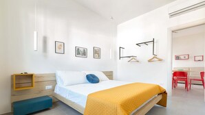 A modern bedroom with a bed, bedside table, and wall-mounted shelves.