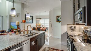 Una cucina moderna con piani in granito, elettrodomestici in acciaio inossidabile e illuminazione a sospensione.