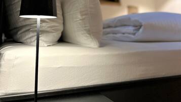 A bed with white bedding and a modern floor lamp.