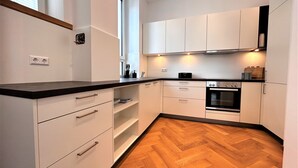 A modern kitchen with white cabinetry, a black countertop, and a herringbone wood floor. - Historical Luxury Homes - Luxus Familien Suite (Freiburg im Breisgau)