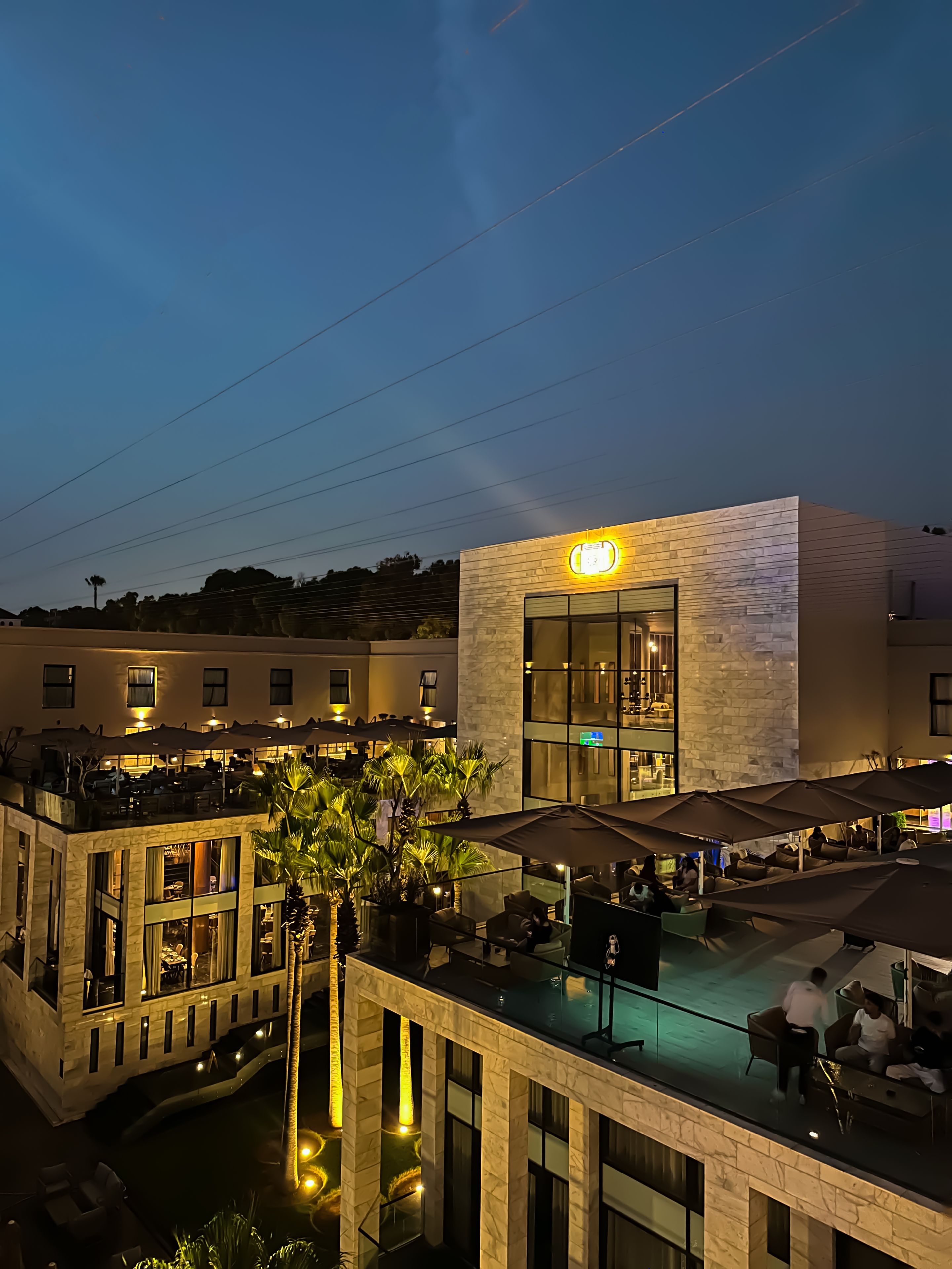 Un hôtel doté d’une terrasse, d’une piscine et d’une entrée bien éclairée.
