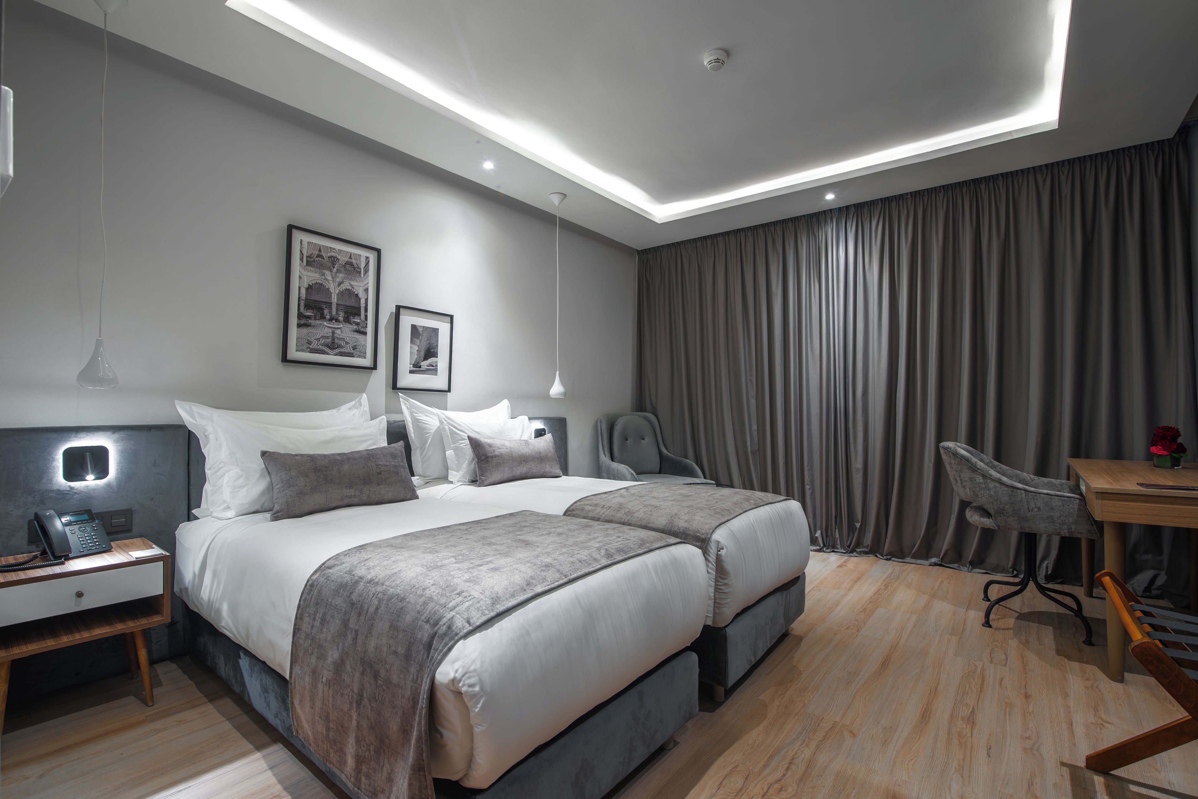 Una habitación de hotel moderna con una cama grande, mesitas de noche, un escritorio y una silla.