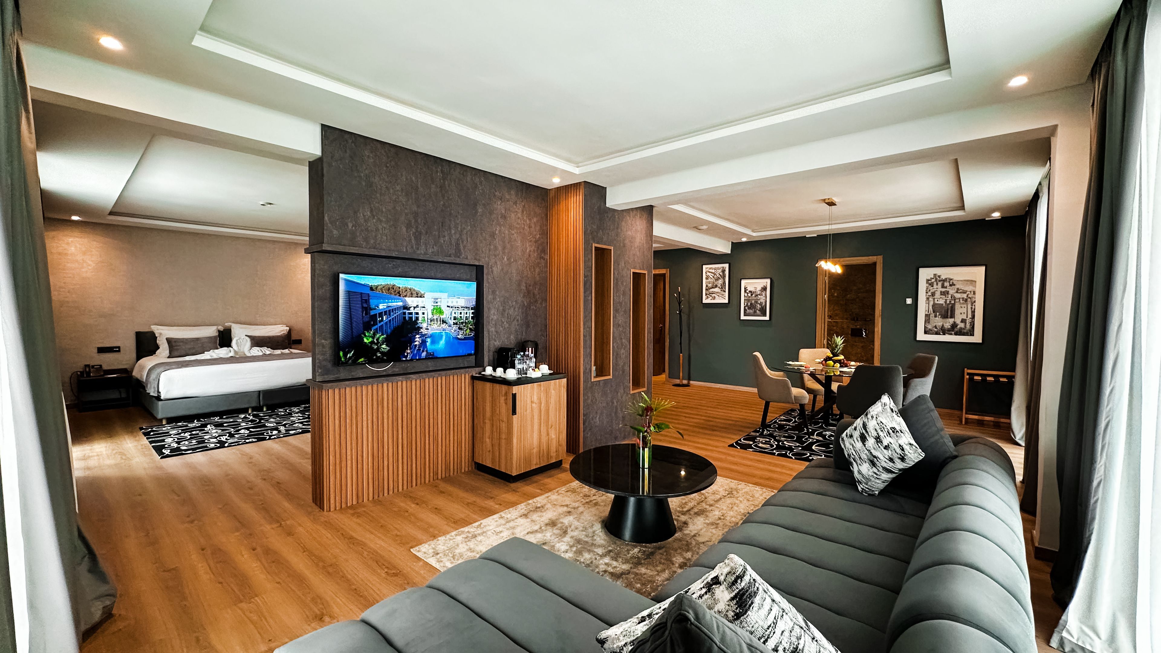 Een moderne hotelkamer met een groot bed, een bank, een televisie, een koffiehoek en kunstwerken aan de wanden.