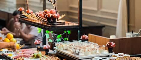 A buffet with various food items and a decorative plant arrangement.