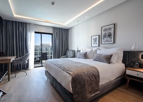 Ein modernes Hotelzimmer mit einem großen Bett, einem Schreibtisch und einem Sessel.