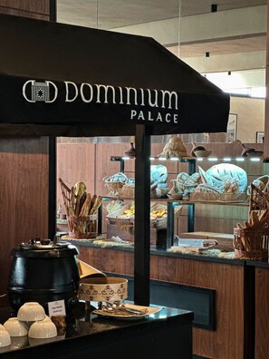 Zona de exhibición de alimentos con cestas de pan y una máquina de café.