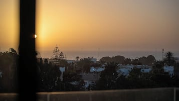 A coastal sunset view with buildings and palm trees.