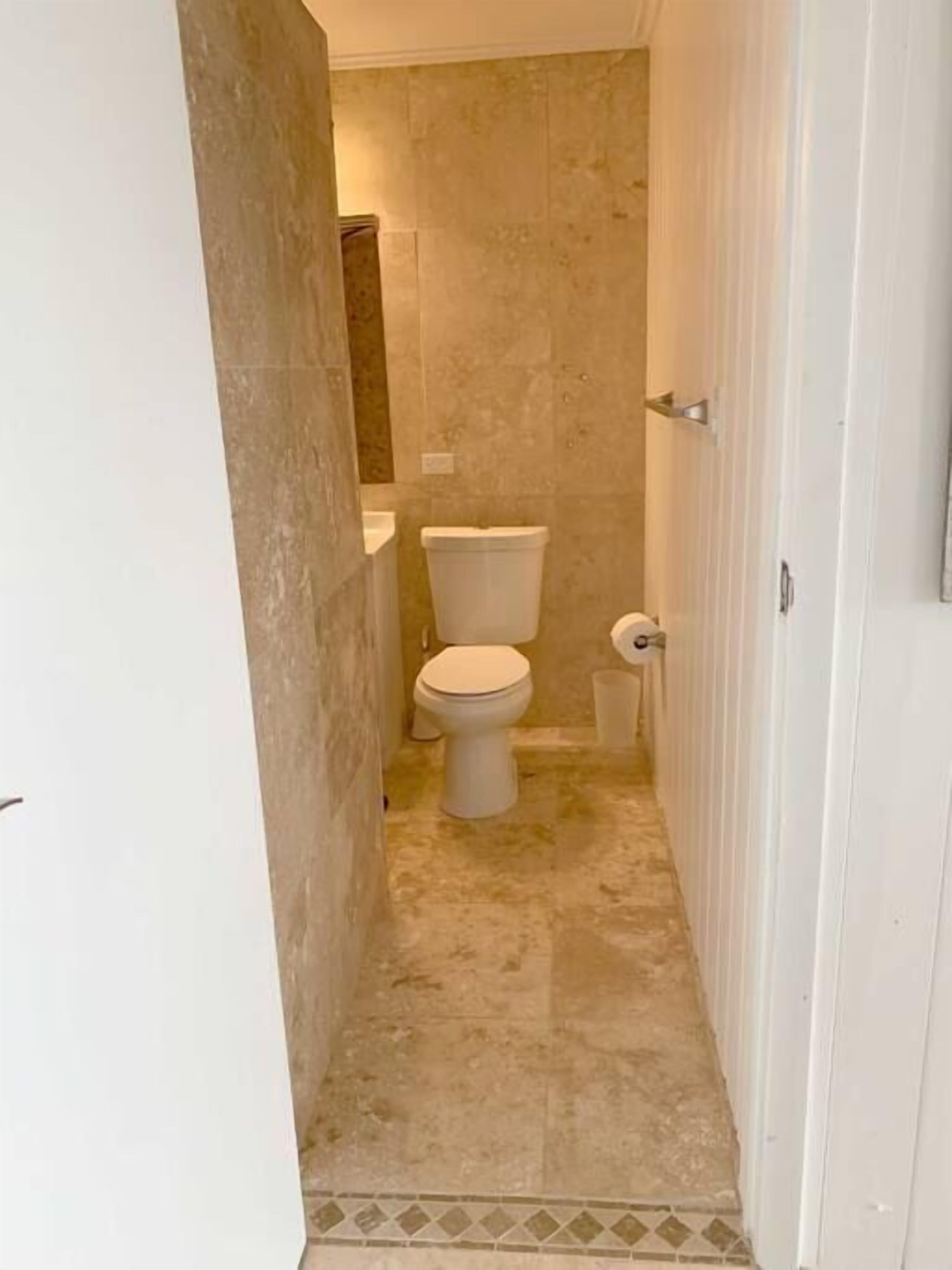 Une petite salle de bain comprenant des toilettes, un lavabo et un sol carrelé.