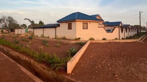 A residential building with a blue roof, a small porch, and a garden area with plants. - Naayina Vacation Villas #AS178
Your Home away from Home (Northern Region)
