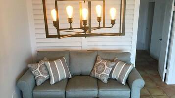 A gray sofa with patterned cushions and a modern light fixture above it.