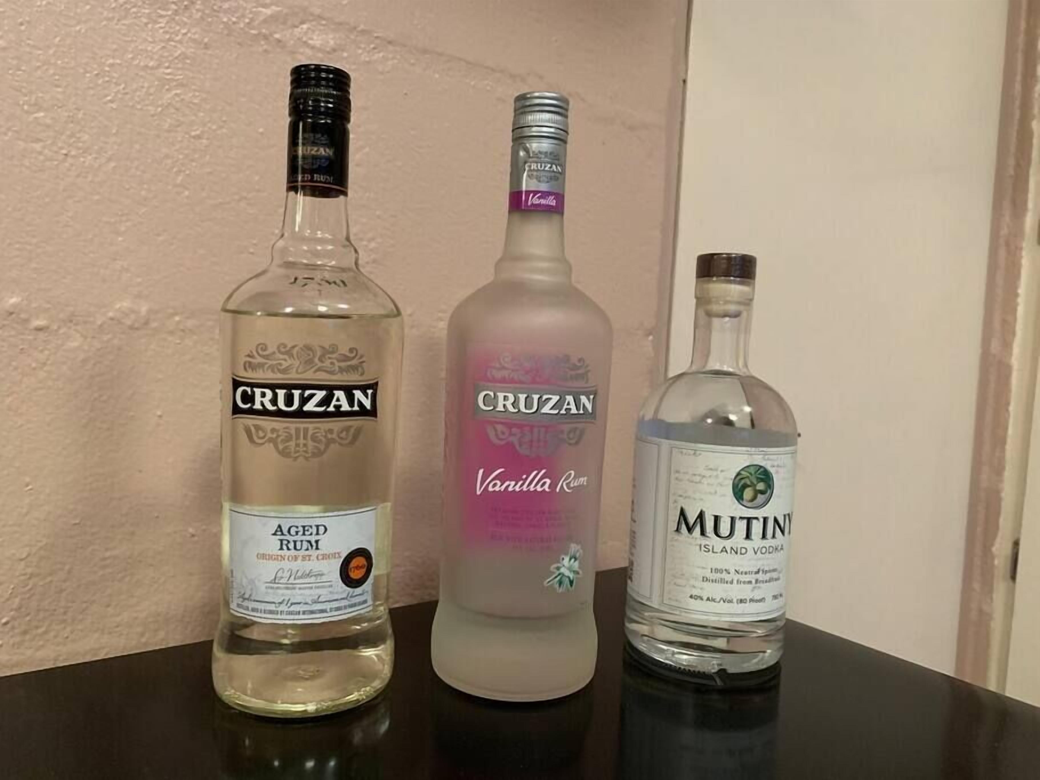 Three bottles of Cruzan rum on a table.