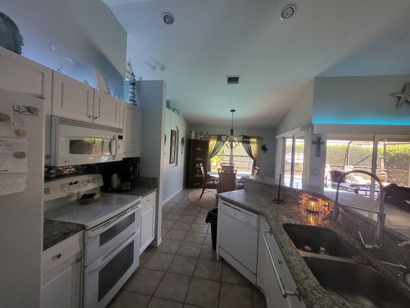 A kitchen with white cabinets, a microwave, a stove, and a sink.