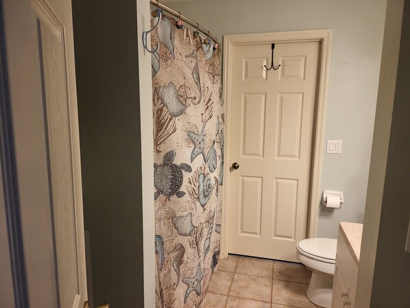 A bathroom with a shower curtain featuring sea creatures, a white door, and a toilet. - Escape to Cape! Heated Private Pool Home (Cape Coral)