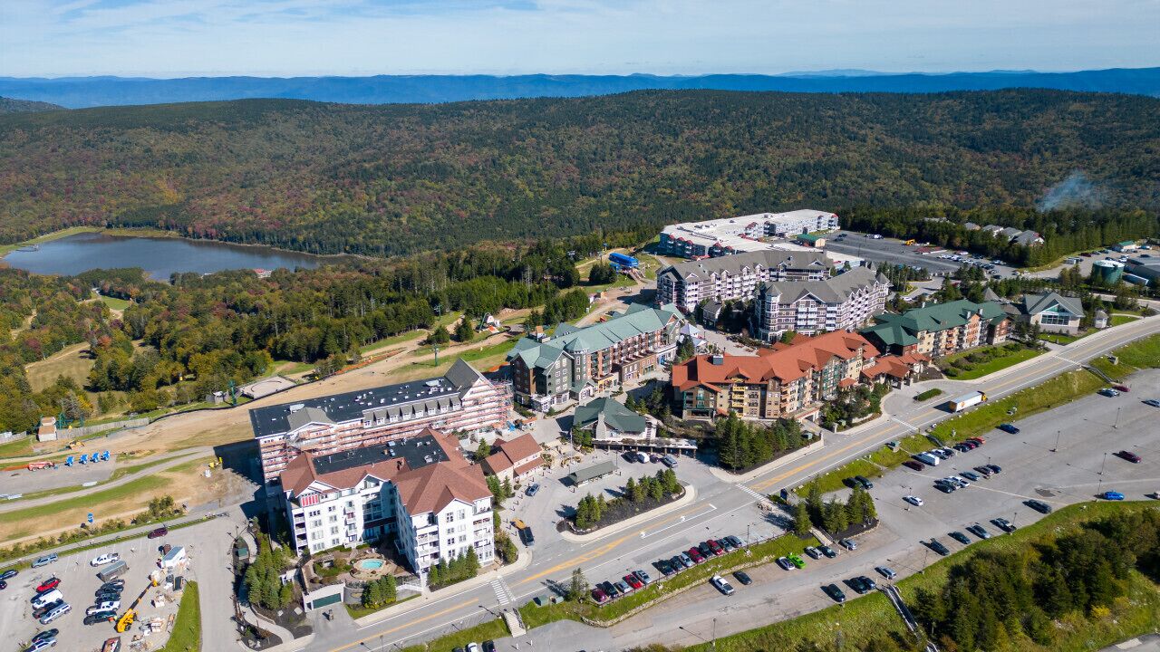 A resort with multiple buildings, a parking lot, and a lake in the background.