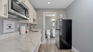 A modern kitchen with a marble countertop, a black refrigerator, and a microwave. - Downtown Studio Loft directly on Front St (Traverse City)