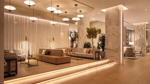 A modern hotel lobby with a wooden floor, a seating area with sofas and a coffee table, and a large plant. - Caesars Republic Scottsdale, a Hilton Hotel (Scottsdale)
