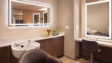 A modern bathroom with a large mirror, a sink, and a chair.