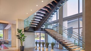 A modern interior with a glass staircase, wooden flooring, and potted plants. - Caesars Republic Scottsdale, a Hilton Hotel (Scottsdale)