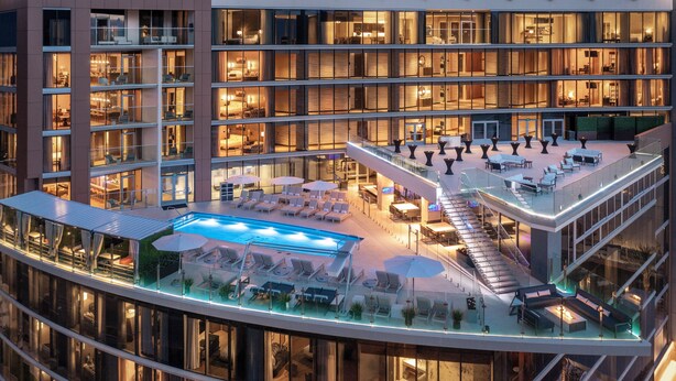 A multi-story hotel with a rooftop pool area, outdoor seating, and a glass-enclosed interior. - Caesars Republic Scottsdale, a Hilton Hotel (Scottsdale)