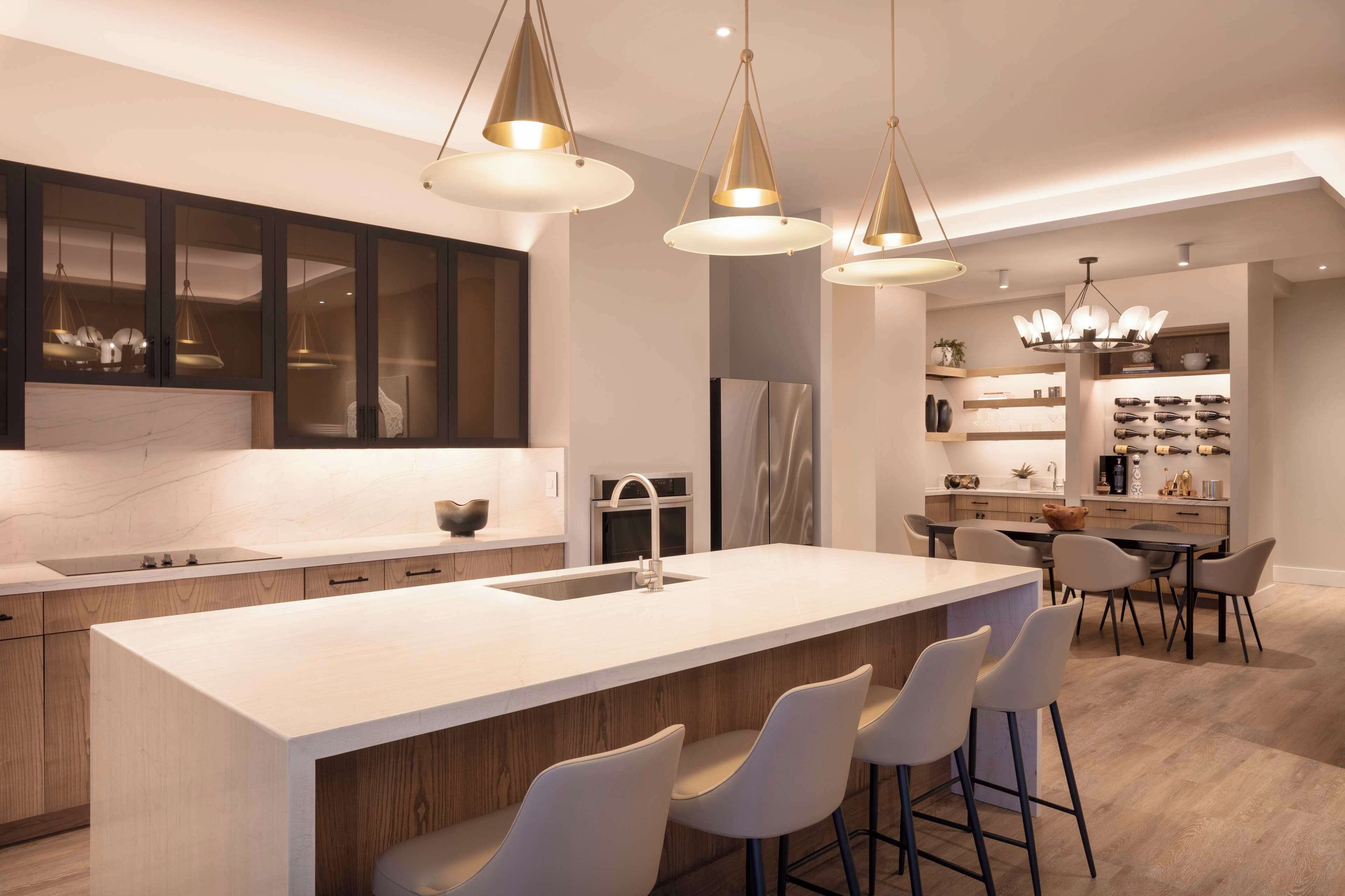 Een moderne keuken met een groot eiland, hanglampen en een eethoek met barkrukken.