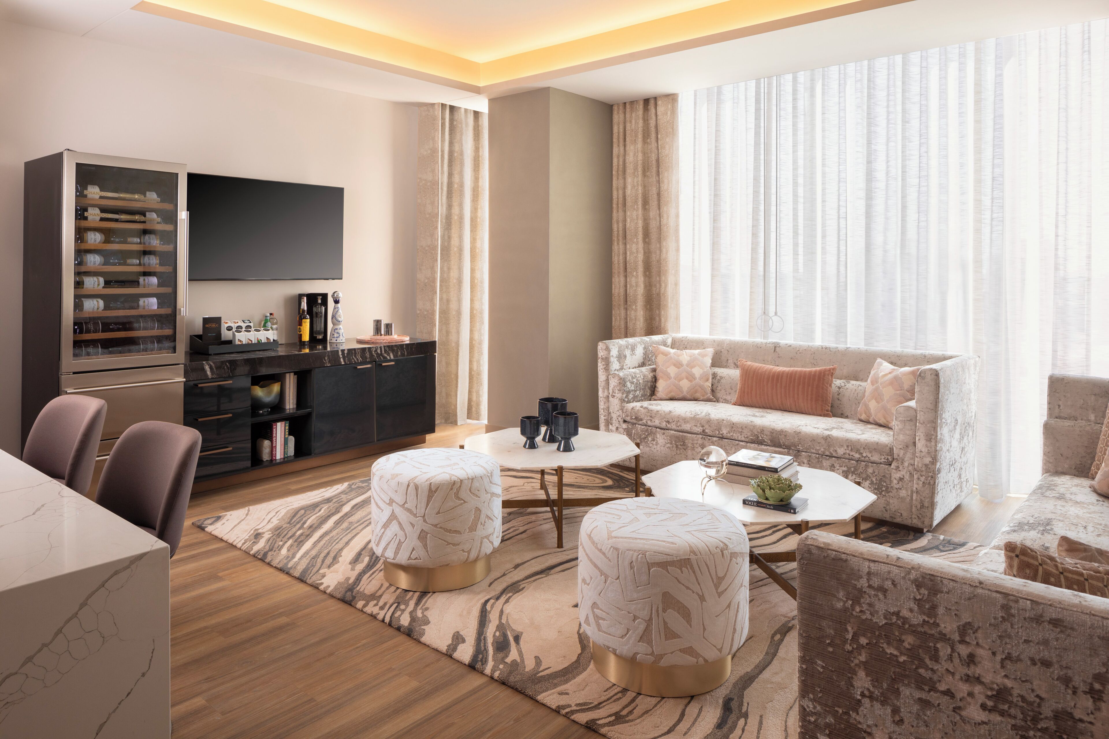A modern living room with a sofa, ottomans, a coffee table, a TV, and a cabinet.