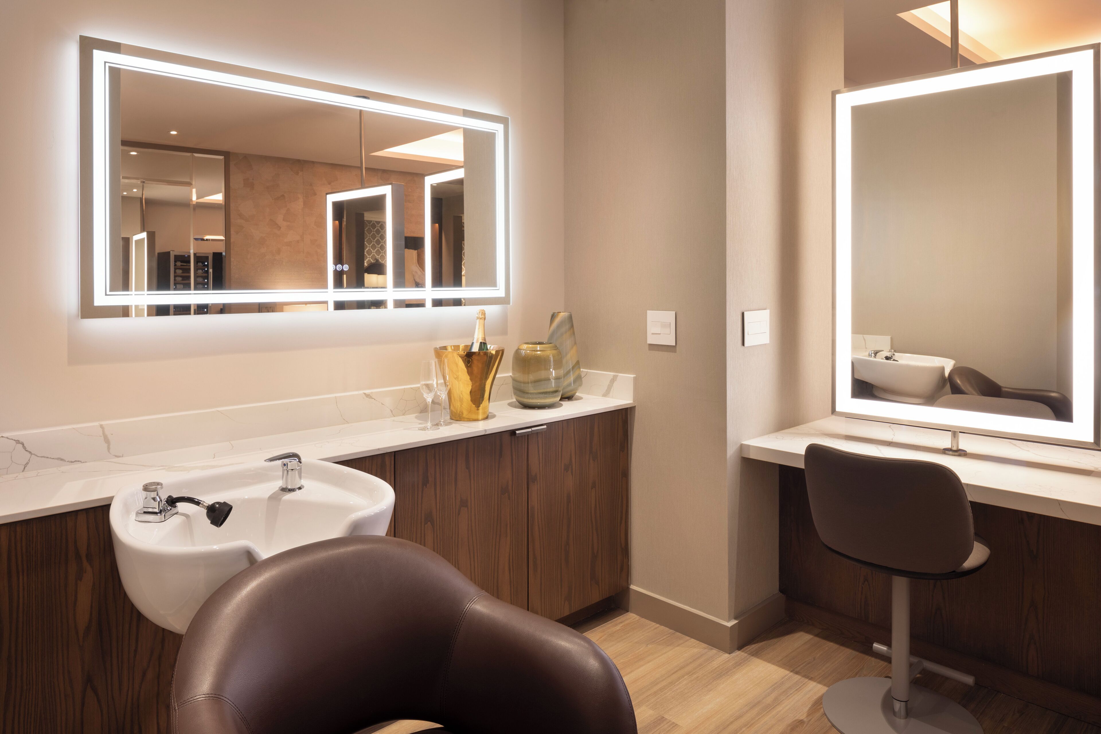A modern bathroom with a large mirror, a sink, and a chair.