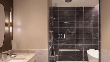 A modern bathroom with a glass-enclosed shower, a freestanding bathtub, and a marble countertop sink.