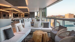 A modern hotel lobby with a seating area, large windows, and a view of the cityscape. - Caesars Republic Scottsdale, a Hilton Hotel (Scottsdale)