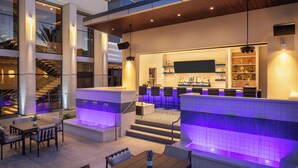 A modern outdoor bar area with seating and a pool. - Caesars Republic Scottsdale, a Hilton Hotel (Scottsdale)
