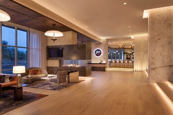 A multi-story hotel with a modern design, featuring a rooftop terrace and a parking area. at Caesars Republic Scottsdale, a Hilton Hotel