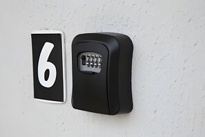A black numeric keypad mounted on a white wall.