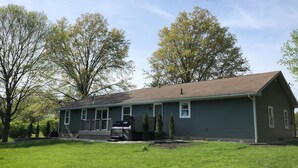 A single-story house with a front porch, a satellite dish, and a well-maintained lawn. - HOT TUB Beauitiful Backyard Oasis Newly Renovated (Middlebury)
