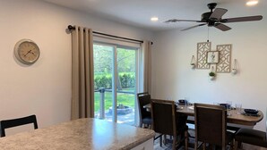 A modern kitchen with a granite countertop, a dining area with four chairs, a ceiling fan, and a clock on the wall. - HOT TUB Beauitiful Backyard Oasis Newly Renovated (Middlebury)
