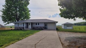 Ein eingeschossiges Haus mit Steinfundament, einer Veranda und einer Garage.