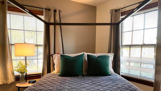 A bedroom with a large bed, a nightstand with a lamp, and a window with blinds. - 1 1 MI to Notre Dame 1stfloor Apt Coffee Bar (South Bend)