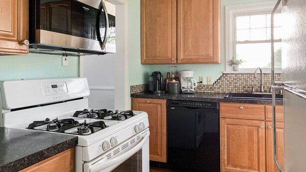A kitchen with a stove, microwave, dishwasher, and wooden cabinets. - HOT TUB 1 2MI to ND Espresso Maker Coffee Bar (South Bend)