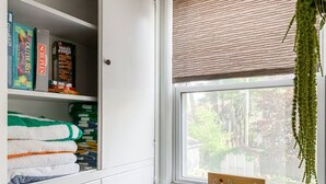A neatly organized storage unit with folded towels and board games. - HOT TUB 1 2MI to ND Espresso Maker Coffee Bar (South Bend)